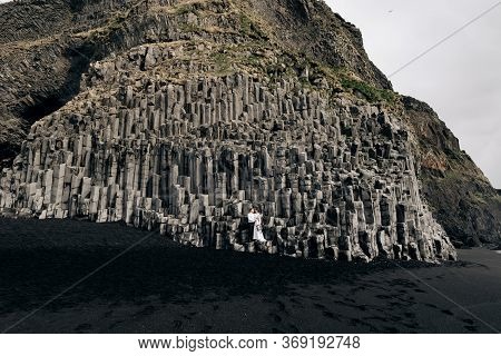 A Wedding Couple Stands On A Wall Of Stone Pillars. The Bride And Groom Are Hugging On Basalt Kekurs