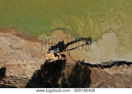 Environmental conservation issue. Machinery mining river, causing siltation and pollution