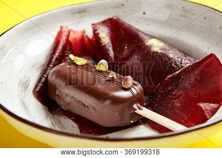 Chocolate mousse dessert close up. Luxury restaurant sweet course side view. Ice cream served with pastila in deep craft plate. Fancy confectionery dish with jellied fruit sweetmeat. Sweet food