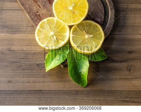 Top view of lemon and green leaves on wooden background