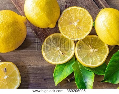 Top view of lemon and green leaves on wooden background