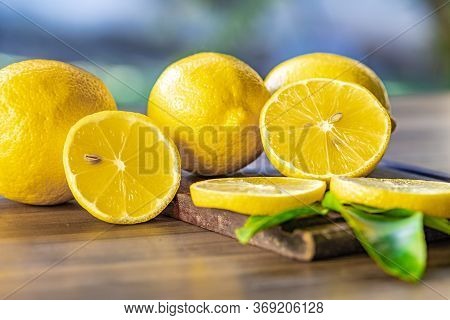 Top view of lemon and green leaves on wooden background
