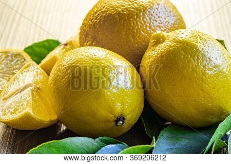 Top view of lemon and green leaves on wooden background