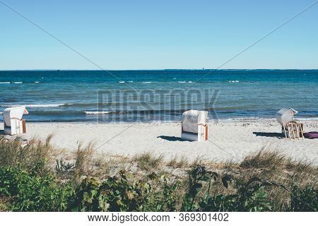Canopied Beach Chairs On Sand Beach Against Baltic Sea And Clear Blue Sky