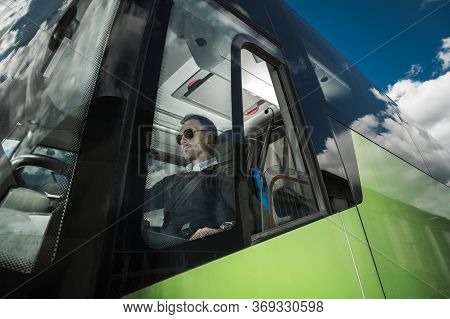 Modern Bus Coach Driver Job. Caucasian Men Behind International Bus Steering Wheel. Transportation I