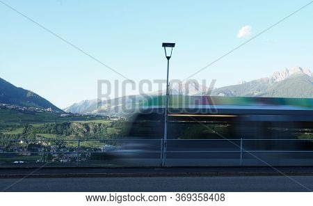 Colourful Photography, A Blurred Regional Train In Merano, South Tirol, Italy. Peak Ifinger On The R