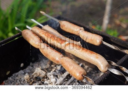 Close Up Of Toasted Sausages On Skewers. Succulent Kupaty Roasting On Chargrill. Concept Of Picnic O