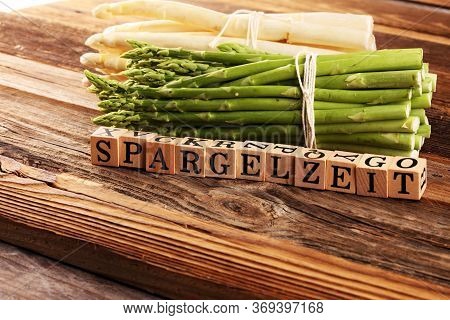 White And Green Asparagus On Background With The German Word Spargelzeit In Wooden Letter.