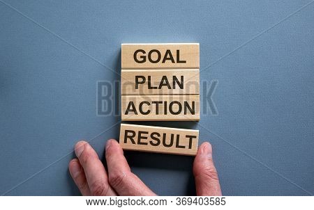 Wooden Blocks Form The Words 'goal, Plan, Action, Result' On Blue Background. Male Hand.