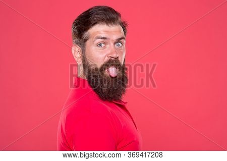 Bearded And Playful. Bearded Man Stick Tongue Out Red Background. Unshaven Hipster With Bearded Face