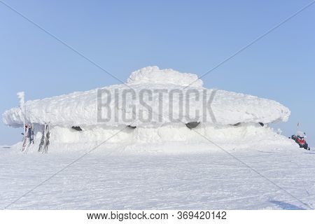 In The Sunlight, This Large, Low Lying Building Is Covered In A Very Thick Layer Of Bright White Sno