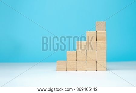 Wooden Blocks As A Pyramid Staircase On Blue Background. Success, Growth, Win, Victory, Development 