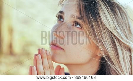 A Young Blonde 18 Year Old Girl Prays With Folded Hands.