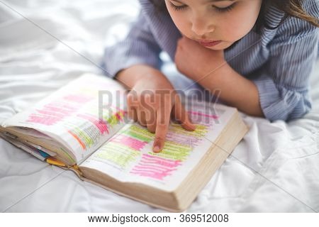 Little Girl Reading From Bible While Lying In Bed. Fetita Citind Din Biblie In Timp Ce Sta Intinsa I