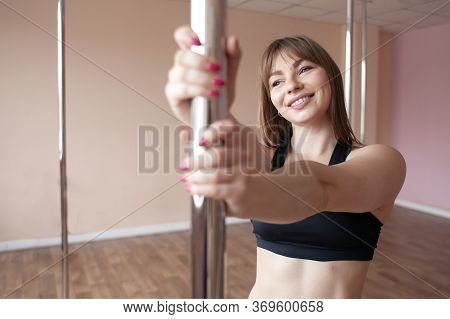 Young Sports Girl In Pole Dance Training, Novice Gymnast Stands In The Hall Smiling And Holds A Pylo