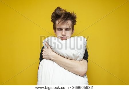 Tired Sleepy Student With A Pillow Is Sad On A Yellow Background, The Guy Has A Problem With Sleep