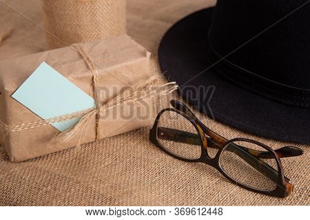 Gift Box On The Table.nearby Glasses And Hat.fathers Day Congratulation Concept
