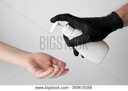 Someone Gives A Disinfectant Gel To The Hands Of Another Person