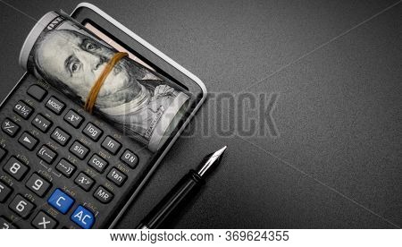 calculator and a roll of us dollarts on desk.