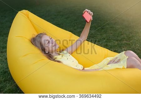 Happy Girl Resting In Nature, Lying On An Inflatable Sofa And Taking A Selfie