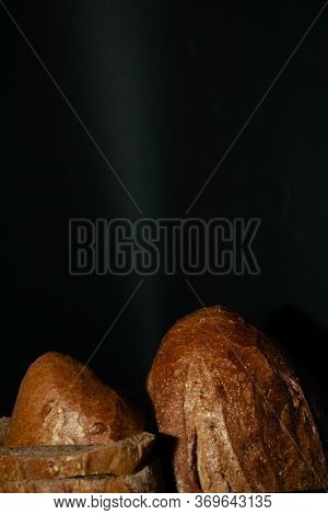 Edge Of Fresh Dark Loaf Of Bread On Black Background. Yeast Product.