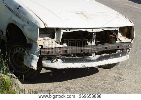 An Old Sprawled Rusty White Passenger Car Abandoned In A Public Parking Lot. Car Trash.