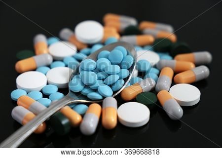 Pills And Capsules, Spoon With Different Medication And Tablets Scattered On A Dark Glass Table. Con
