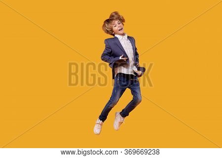 A Little Boy In A White Shirt In Full Growth Bounces And Is In The Air.