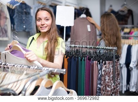 Smiling Young Woman Choosing Pullover In Shop