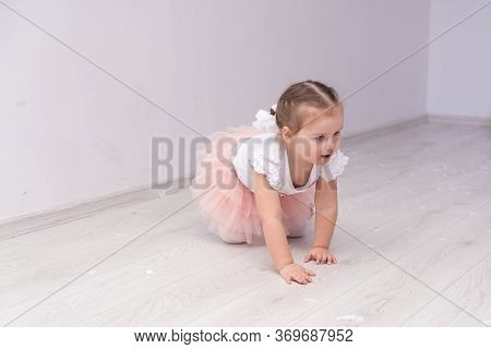 Little Girl In A Fluffy Yuka Crawls On A Wooden Floor.