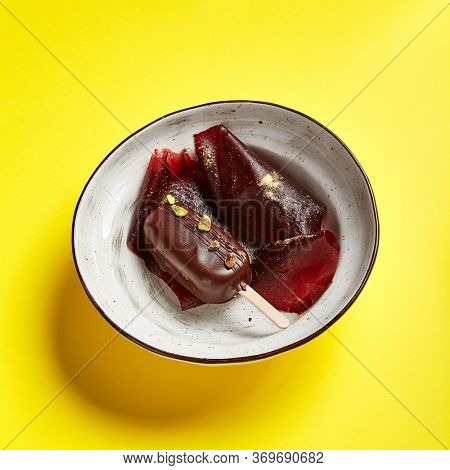 Chocolate mousse dessert top view. Luxury restaurant sweet course side view. Ice cream served with pastila in deep craft plate. Fancy confectionery dish with jellied fruit sweetmeat. Sweet food