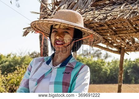 Taungoo, Myanmar - January 26, 2020: Burmese Woman In Traditional Thanaka Makeup And Straw Hat