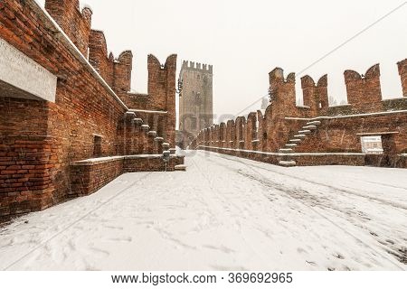 Ancient Scaligero Bridge Of Castelvecchio In Winter While It Snows. Old Castle In Verona, Unesco Wor