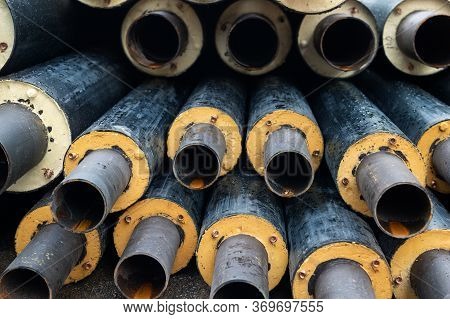 Heap Of Many New Black Insulated Steel Pipes At Municipal Construction Site Outdoors. Heating Main D