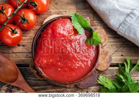 Tomatoes In Their Own Juice Or Tomato Paste In A Wooden Bowl And Fresh Tomatoes On A Rustic Wooden T