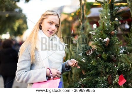 Portrait Of Beautiful Blond Young Woman Choosing A Christmas Tree