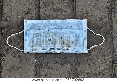 Trash A Simple Medical Protective Mask Lying On Graund During The Covid-19 Pandemic. Environmental P