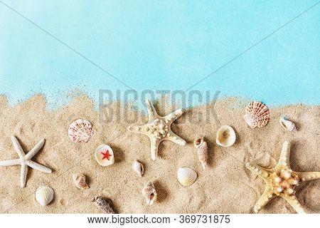 Golden Sea Sand With Starfish And Shells On Pastel Blue Background Top View. Summer Sea And Beach Ba