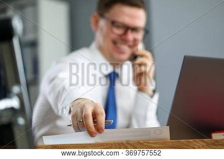Close-up Of Persons Hand Taking Paper And Talking On Smartphone. Businessman In Presentable Suit Wea