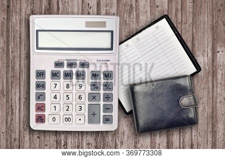 Office Flat Lay Composition With Calculator, Address Book And Black Purse On Brown Wooden Table Back