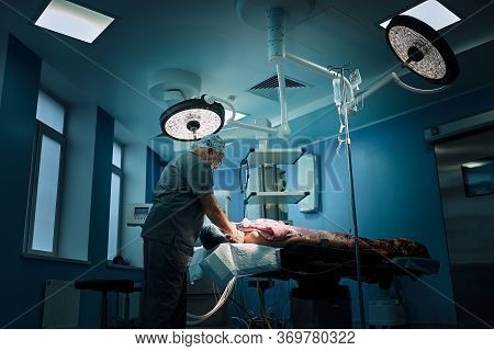 An Anesthetist Prepares A Patient For Surgery. Team Of Surgeons At Work In The Operating Room.