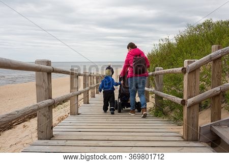 City Carnikava, Latvia. The Mother Walked Along The Sea With Her Child And Pram.03.06.2020