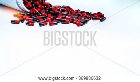 Red-black Antibiotic Capsule Pills Spread Out Of Plastic Drug Bottle On White Background. Antibiotic
