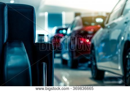 Blurred New Luxury Red And Gray Car Parked In Modern Showroom. Selective Focus On Black Leather Sofa