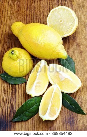Fresh Ripe Lunario Lemons Full Body And Halves With Leafs Closeup On Wooden Background