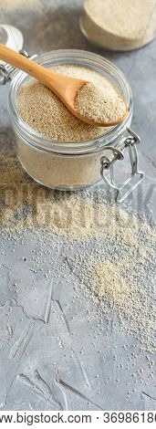 Raw Uncooked Fonio Seeds In A Glass Jar With A Spoon On Grey Background Close Up With Copy Space