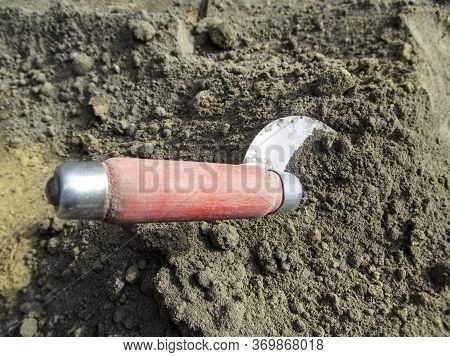 Trowel Stuck In A Dry Sand-cement Mixture, Close-up. Construction Tool For Kneading Or Taking Materi