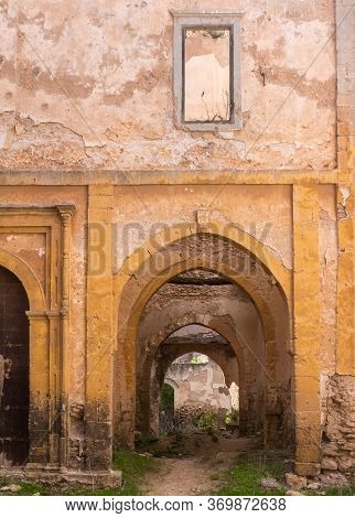 Abandoned Old Ruined Building. Gate With An Arc Without Door. Ruined Facade Of The Walls. Dar Caid H