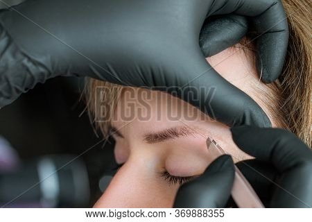 The Master Corrects The Eyebrows With Tweezers. Close-up Photo