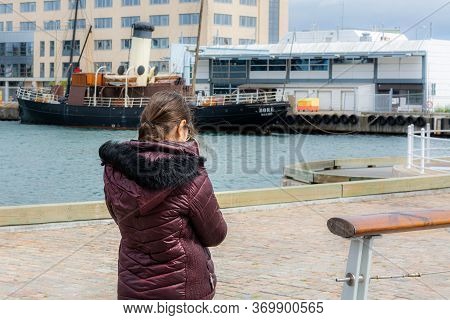 Malmo, Sweden - May 17, 2020: Young Girl Walking In The Inner Harbour With The Old Steamboat Bore In